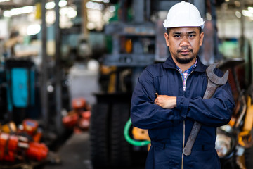 Portrait of Asian mechanic Fold over holding a wrench and smiling at truck and forklift garage. Industrial mechanic Engineer in Hard Hat © NVB Stocker