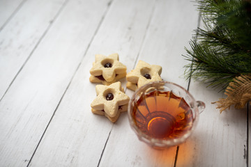 Christmas shortbread star cookies with strawberry jam. Festive atmosphere holiday pastry baking concept. Cookies and tea for Santa