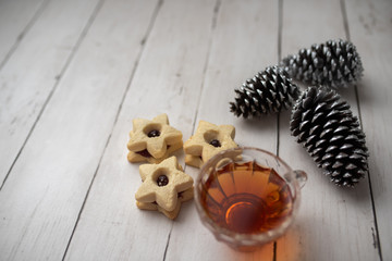 Christmas shortbread star cookies with strawberry jam. Festive atmosphere holiday pastry baking concept. Cookies and tea for Santa
