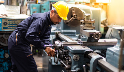Factory Asian male worker. Asian man Lathe worker in production plant drilling at machine on the factory. Yellow hard hat safety first at mechanic factory. - obrazy, fototapety, plakaty