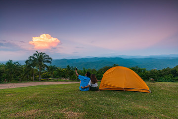 The lover traveler with her tent on the cliff in the evening.