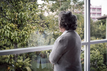 back view, Portrait of elderly Asian senior woman with grey hair looking out window for thinking...