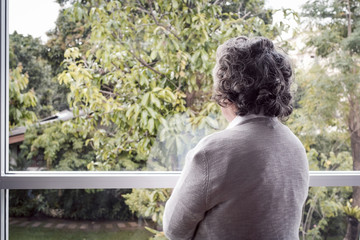 back view, Portrait of elderly Asian senior woman with grey hair looking out window for thinking...