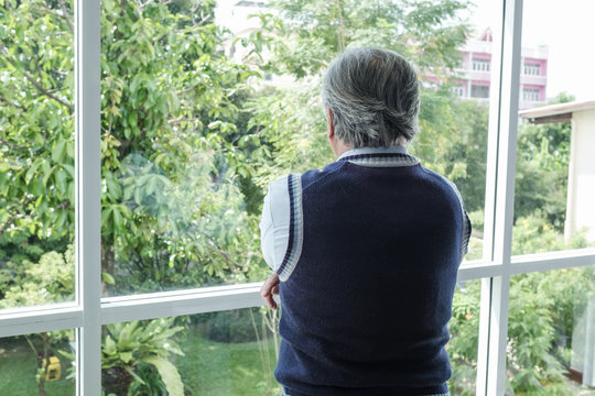 back view portrait of elderly Asian senior man with grey hair looking out window for thinking business seriously, business lifestyle concept