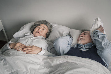 elderly couple caucasian senior man and woman sleep on bed and snoring in white blanket in bedroom,...