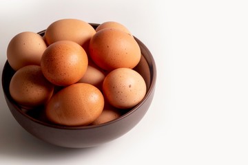brown eggs in a bowl on white background with copy space 