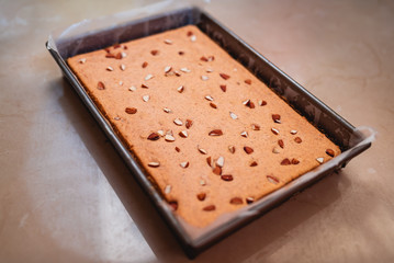 Baked banana bread and almond dry cake in a long metal pan. Small bakery homemade cake isolated in a brown marble background. freshly prepared cake advertisement and pamphlet for small businesses.