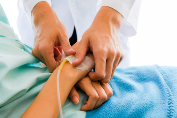 Close up male doctor holding Asian female patient hand at hospital bed and hand with fluid replacement therapy, saline intravenous for set,Healthcare and medically concept