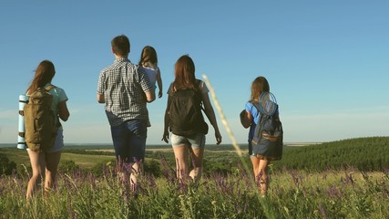 travelers admire the beautiful scenery and nature. teamwork of tourists. travelers go with backpacks through meadow. Family of tourists with children in the countryside. movement to victory.