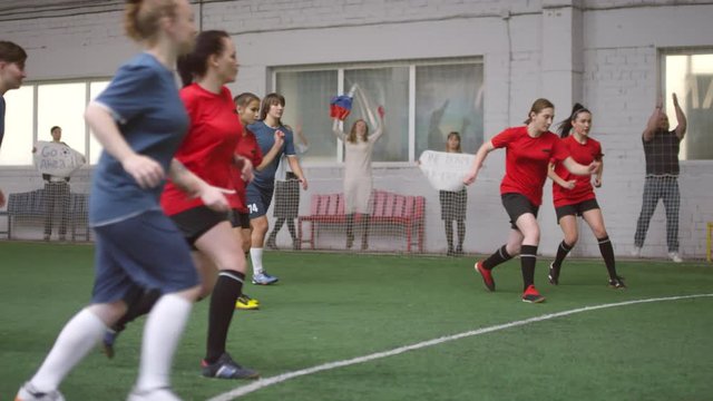Slow motion shot of professional female soccer player in sports uniform taking penalty shot and scoring a goal during game on indoor field