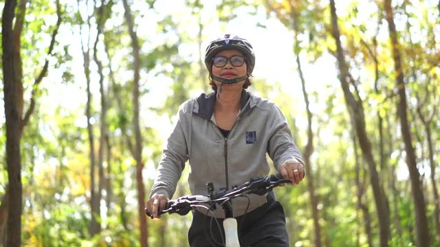 Slow motion Senior asian woman riding bikes in park
