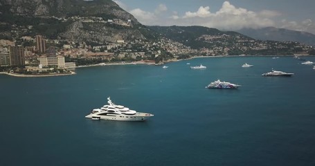 Aerial Drone collection of Luxury Yachts outside Monaco in French Riviera with mountains backdrop