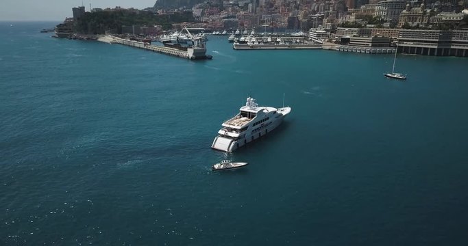 Aerial view of large Luxury Yacht outside Monaco with Port Hercules Monaco in background