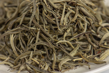 Close up of premium quality dried white tea leaves in small dish.