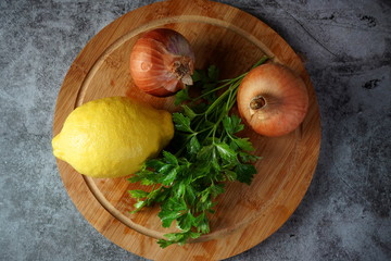 onion, parsley and lemon on cutting Board on dark background