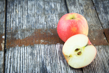 Red apple cut in half old wood table .
