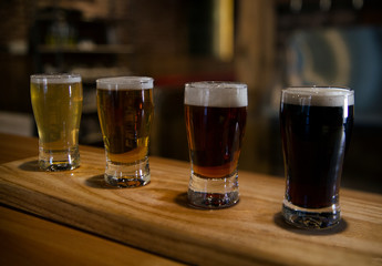 Bar table with different craft foamy beers in glasses 