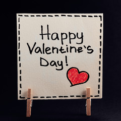 The sticker with the greeting happy Valentines day on the clothespin on a dark background. - 310573849