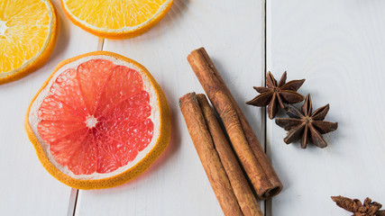 Dried slices of lemon and grapefruit, star anise and cinnamon on a light wooden table.