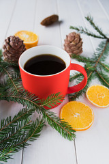 Red cup with a hot drink next to spruce branches and dried lemon slices