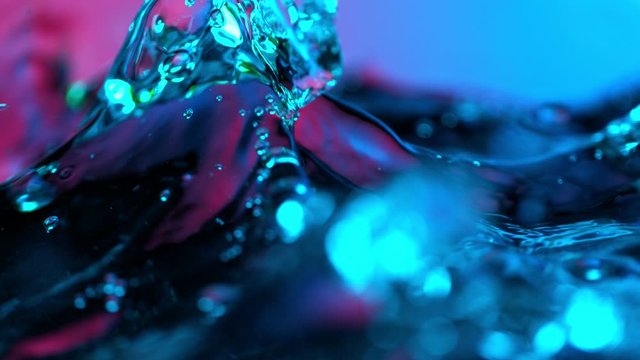 Super slow motion of splashing water wave illuminated by neon lights. Filmed on very high speed camera, 1000 fps.