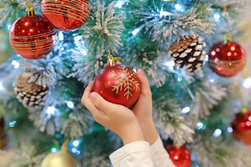 Close-up hands of children holding christmas ball of christmas tree in the winter season and happy new year.