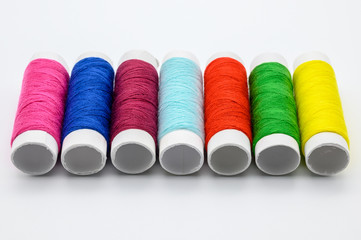 Sewing kit with measure tape, pins, colorful threads isolated on white background.