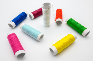 Sewing kit with measure tape, pins, colorful threads isolated on white background.