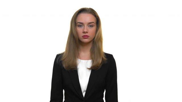 A close-up of a woman wearing business attire, staring into the camera with a neutral expression, on a seamless white studio background