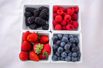 strawberries, blueberries, blackberries and raspberries in the each square bowl