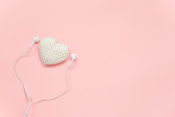 Decorative textile volume heart and white headphones on pink background. Concept Listen to your heart. Top view Copy space Flat lay Template for your design, postcard