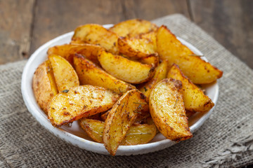 Baked potato with spices in a plate on the rustic table.