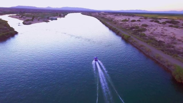 Aerial footage following a speedboat over the Colorado River at sunset, landscape horizon in the distance