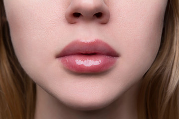 Close up beautiful woman's plump sexy full lips with nude lip gloss