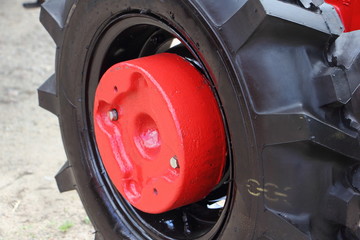 New Red wheel weight on walk-behind tractor wheel disc close up, external farming equipment