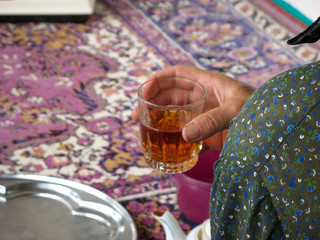 Rural woman holding a glass of tea and also called chay or chai. Close up of female hand with a cup of tea from back.