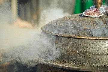 Steam coming out from traditional iron cooking pot 