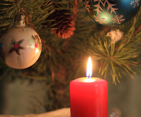 A decorated Christmas tree and a red lighted candle