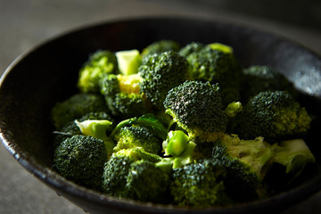 Boiled broccoli in black bowl  - obrazy, fototapety, plakaty