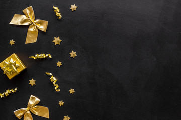 New Year decoration background - golden bows and presents - on black desk top-down frame copy space