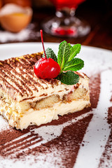Italian food concept. Coffee dessert Tiramisu made with Savoyardi cookies and mascarpone cream, a knife and a fork of cocoa. Serving dishes in a restaurant. background image