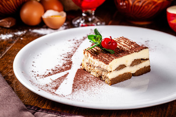 Italian food concept. Coffee dessert Tiramisu made with Savoyardi cookies and mascarpone cream, a knife and a fork of cocoa. Serving dishes in a restaurant. background image