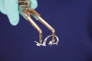 Dentist's hand in glove with dental tongs and clasp.