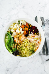 Healthy pumpkin seasonal bowl. Salad with meat, cheese, bulgur and vegetables on marble background. Copy space