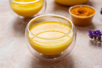 Masala Haldi Doodh. Healthy  golden milk with turmeric and honey on a beige marble background.