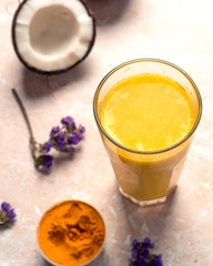 .Masala Haldi Doodh. Healthy vegetarian coconut golden milk with turmeric and honey on a beige marble background.