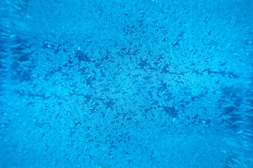 Ice freezes on glass in the cold winter season. Beautiful blue patterns left by frost on the window create the atmosphere of the New Year or Christmas holiday or other event.