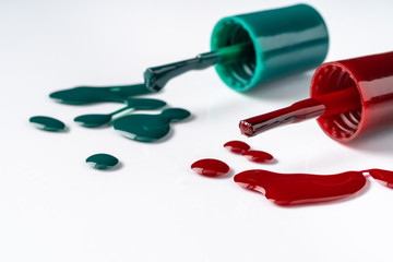 Bright colored nail polish bottles with drippings on white background