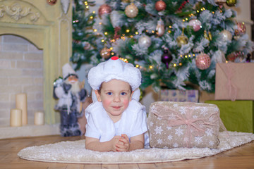Obraz na płótnie Canvas Little boy under the Christmas tree. New year and Christmas. Young child. Bunny costume. The lights on the tree. Flank. Christmas decoration.