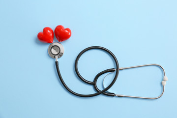 Stethoscope and red hearts on color background. Cardiology concept